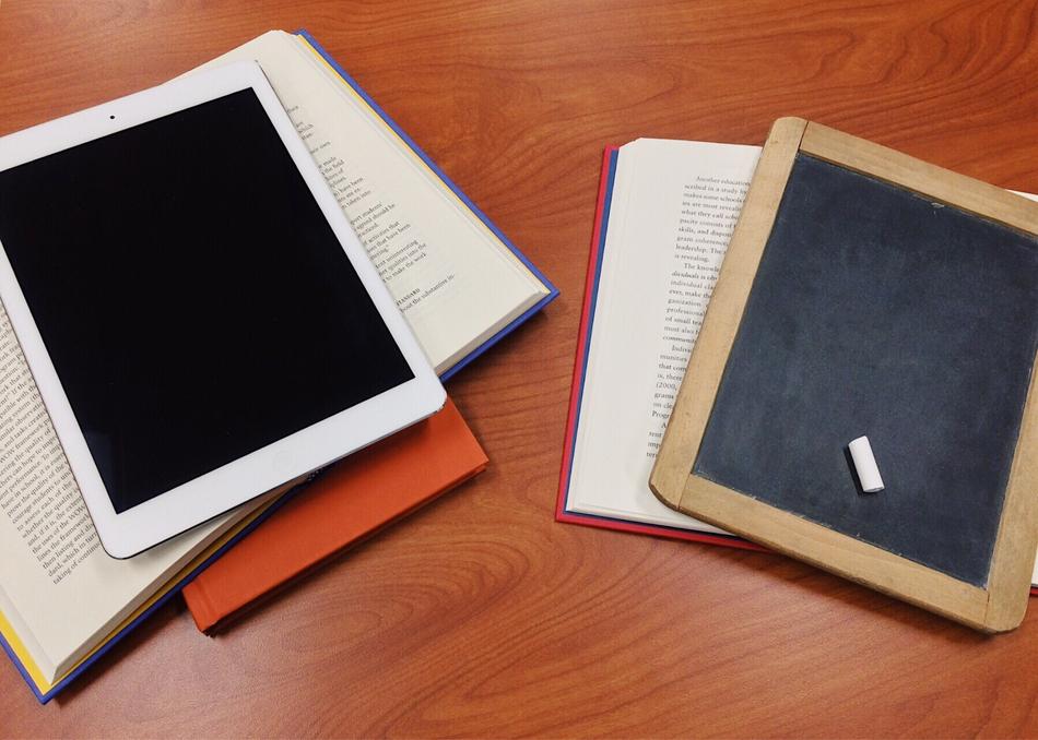 Colorful books, board and tablet, on the wooden table in light