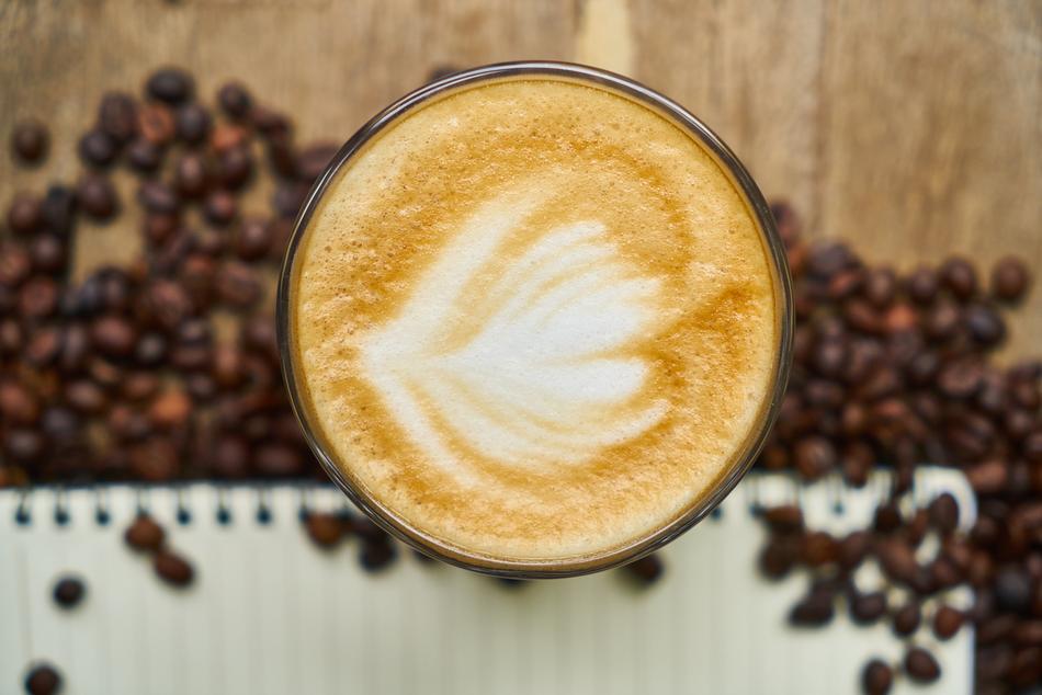 pattern on cappuccino foam on the background of coffee beans