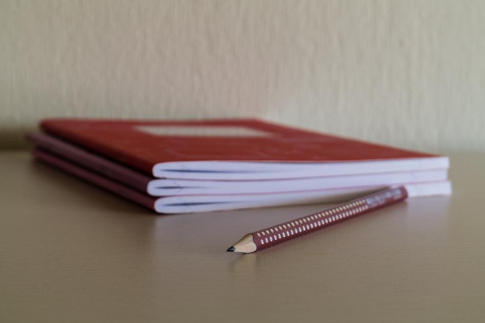 Close-up of the red and gold pencil, near the notebooks, on the desk