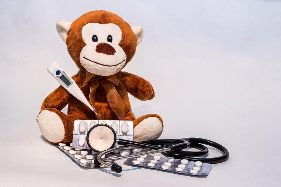 plush toy, pills and stethoscope on white background