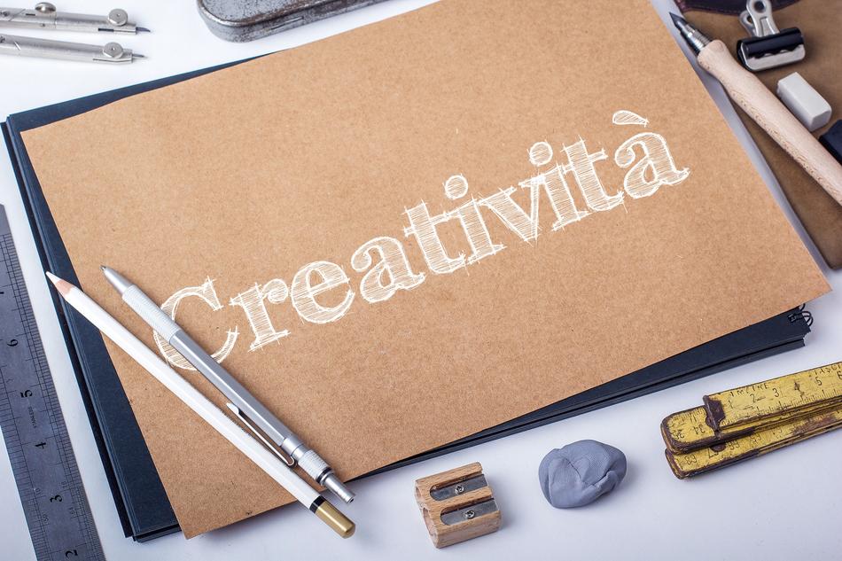 Drawn, white 'Creativita' word on the wooden board, among the tools