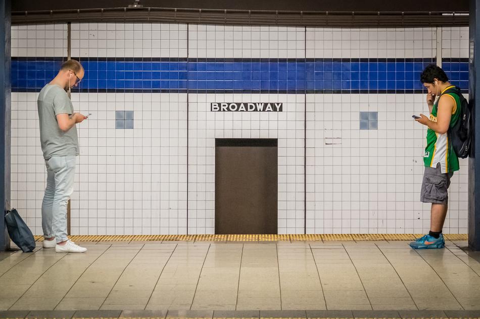 two men with phones at a subway station