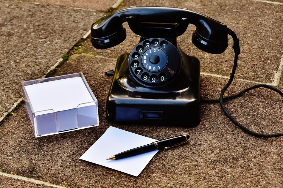 Glossy, black phone from the 1955, near the notes and black pen