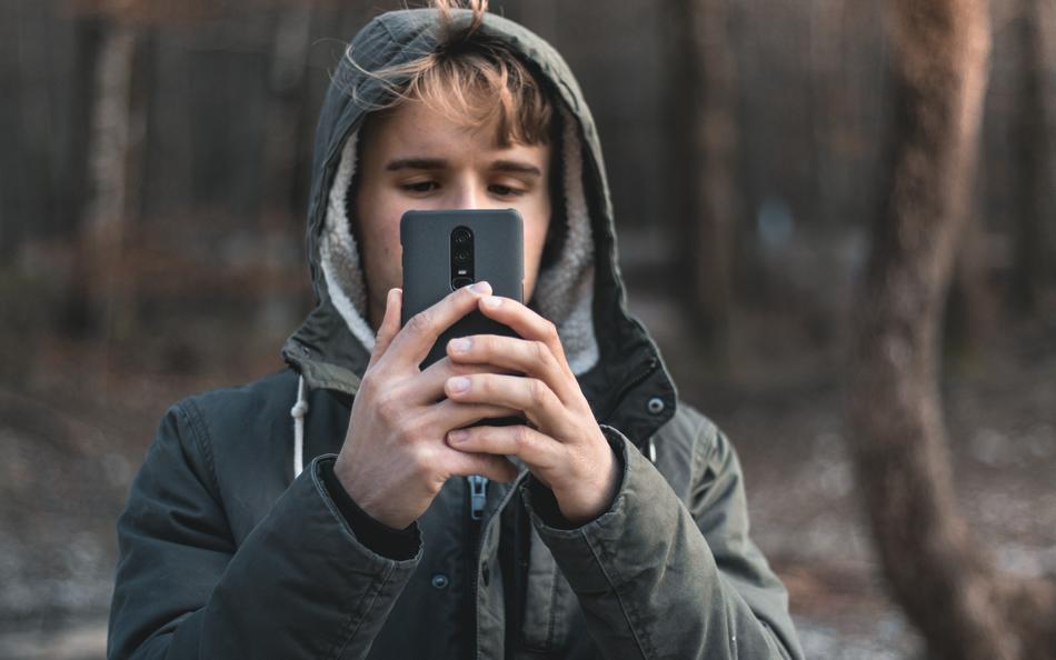 young Boy with smartphone in forest at winter