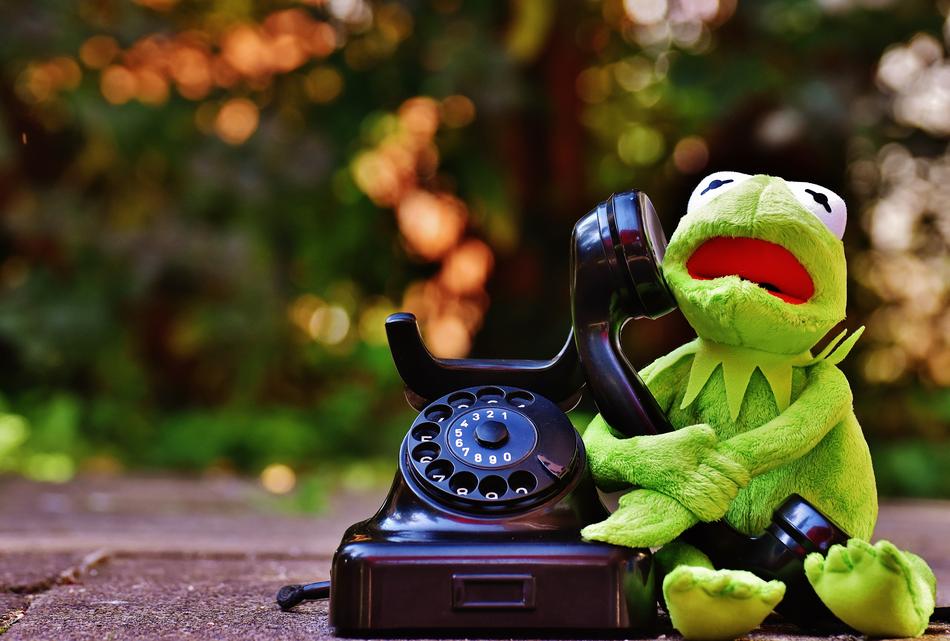 funny frog figurine with retro phone on blurred background