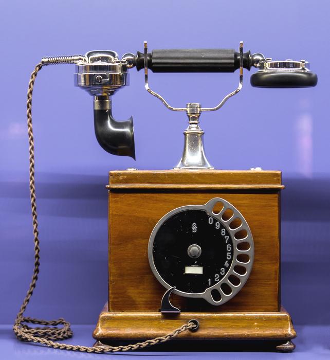 antique wooden telephone on a purple background
