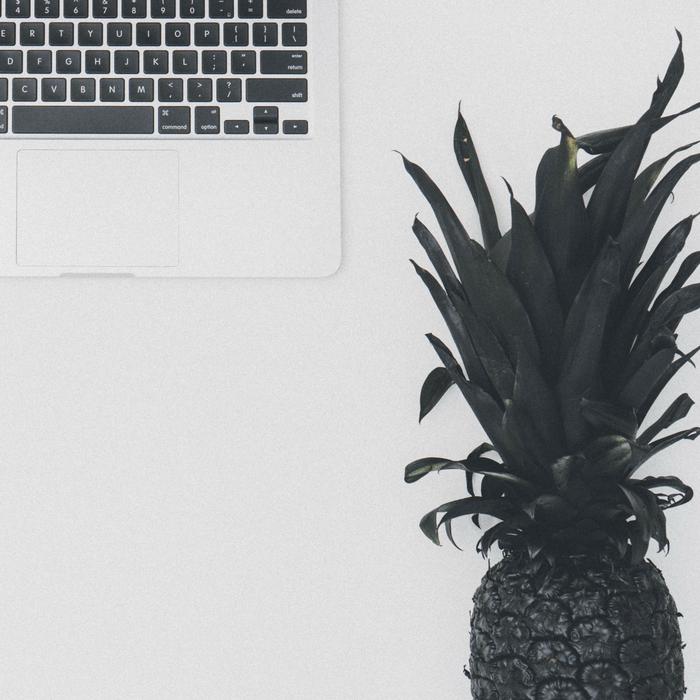 Black and white photo of the beautiful pineapple, near the laptop