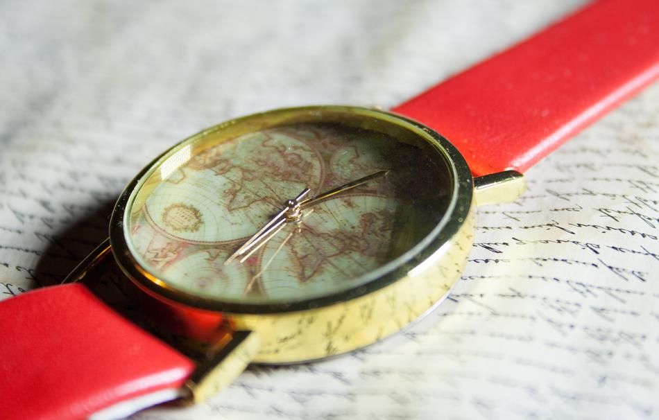 Close-up of the shiny clock with the World Map, with the red belt, on the book