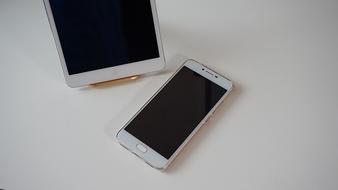 White smartphone and and tablet, on the white surface