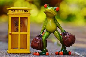 funny figurine of a frog traveler near the phone