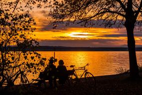 a man with a bicycle on a bench by the lake while ordering