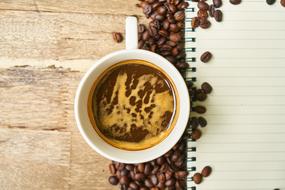 cup with Coffee, beans and blank notebook