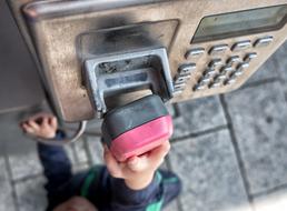 Close-up of the child's hand on the old phone, on the street