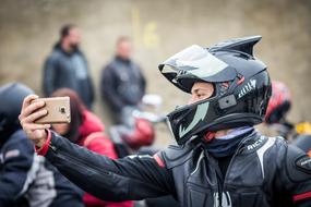 selfie of a motorcyclist wearing a helmet on a blurred background of the crowd