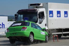 Green car and truck at the crash test, on the road