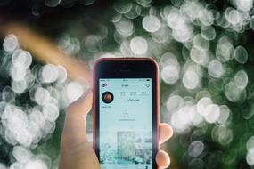 smartphone in hand on bokeh background