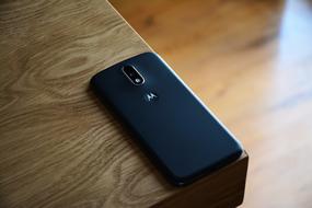 black mobile phone with camera on the edge of the table