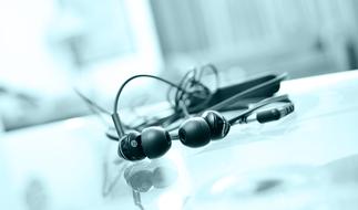 Close-up of the shiny, black earphones on the surface with reflection