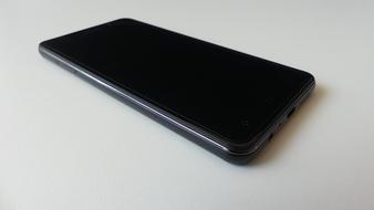 Close-up of the shiny, black smartphone, on white surface