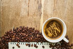 a cup of coffee on the table near coffee beans