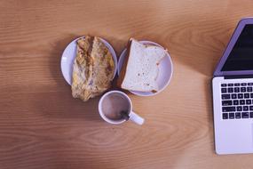 coffee and sandwiches on the table near the laptop