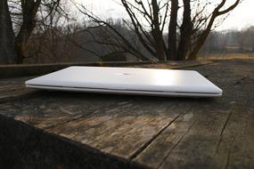 white laptop on a wooden table in the garden