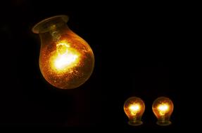 three yellow light bulbs in black background