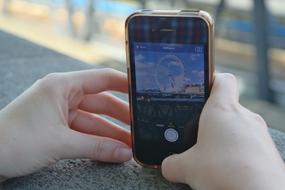 girl photographing a ferris wheel in London on the phone with a blurred background