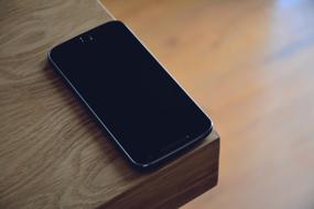 mobile phone on the edge of a wooden table