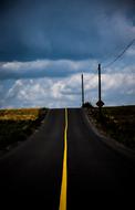 Landscape with the road with yellow line, among the colorful fields, under the clouds