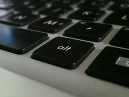 Close-up of the black and white "alt" key, among the keyboard of the laptop, in light