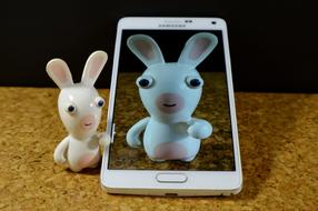 Shiny, white and pink hare figure and white "Samsung" smartphone