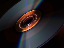 Close-up of the colorful, shiny, turning CD disk, in light, at dark background