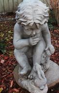 statue of a child in the autumn garden close up