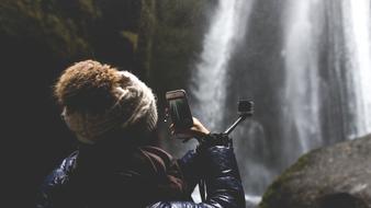 girl with smartphone near the waterfall