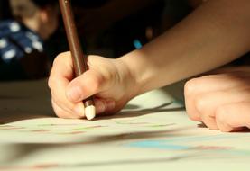 child draws with a brown pencil