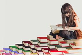 painted reading girl sitting on a pyramid of books