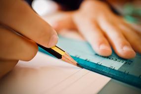 pencil and ruler in hand on a notebook