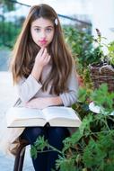 photo of a girl with a big book in the garden