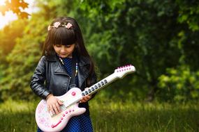 photo of a girl with a toy bass guitar in the park