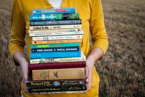 a stack of books in the hands of a girl