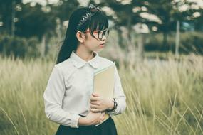 asian schoolgirl with books in the field