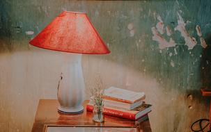 table lamp and books on a bedside table on a background of an old wall