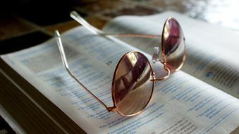 golden sunglasses lie on an open book