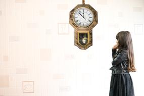 photo of a girl looking at a wall clock