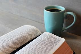 open bible and cup of coffee on a wooden table