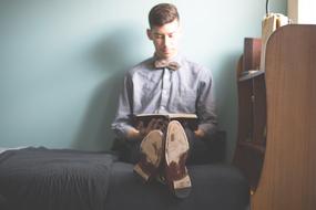student reads textbook on bed