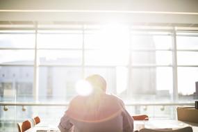 a man sits at a table facing the sun