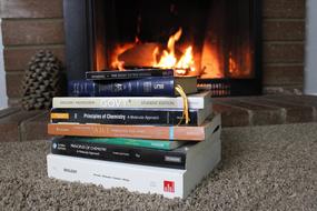 stack of books on a background of a burning fireplace