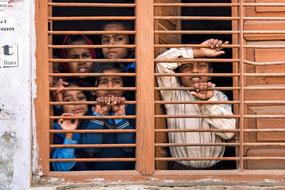 Indian boys look out the window from behind bars